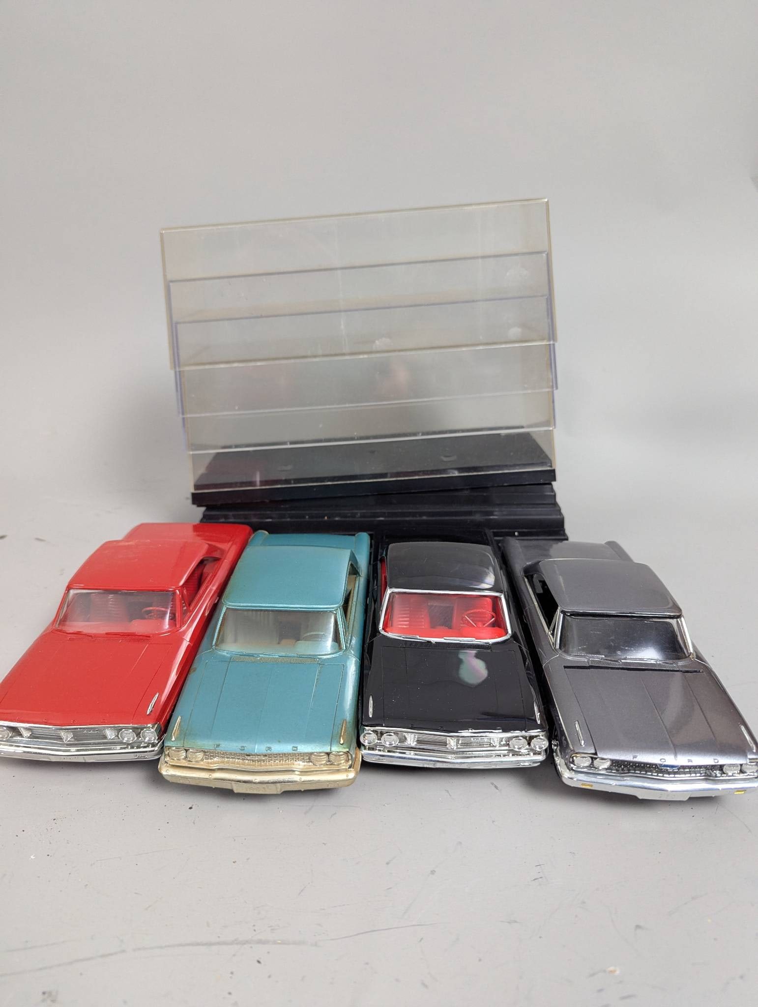 1960s Ford Lot of 4 Promo Model Cars with Plastic Display Cases: Four 1960s Ford promotional model cars featuring vehicles in red, aqua, black, and silver finishes. Each car is made of high-quality plastic, showcasing details typical of Ford models from the 1960s.
