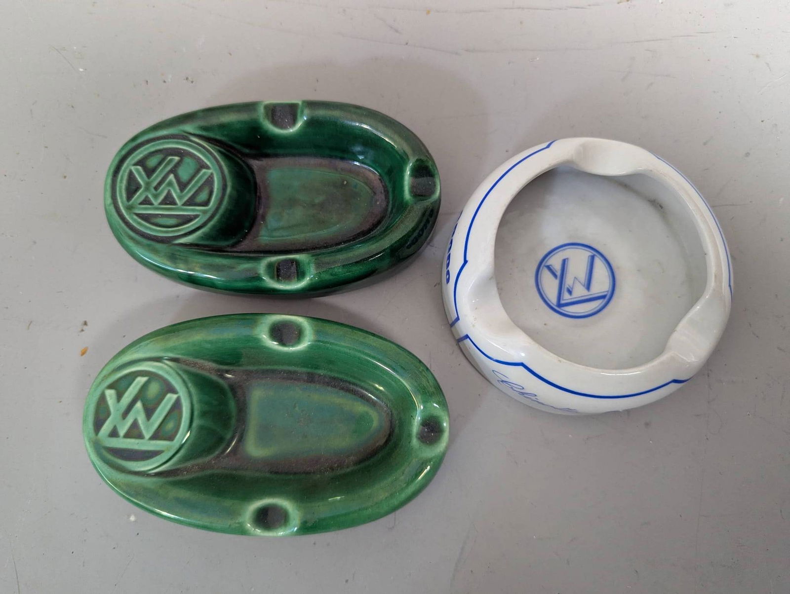 Three Ceramic Wagon-Lits Orient Express Ashtrays by Gien France Monterrey and John Vers: Three ceramic Wagon-Lits Orient Express ashtrays from varied makers. The lot features two green ashtrays marked Gien France, both with an elevated design and measuring approximately 5 inches high, 3 i
