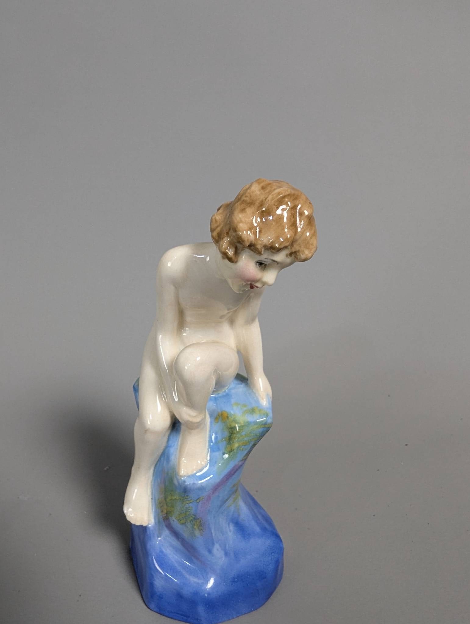 Royal Doulton HN 1543 Dancing Eyes and Sunny Hair Figurine: A Royal Doulton porcelain figurine titled Dancing Eyes and Sunny Hair with model number HN 1543. This figurine depicts a child seated on a colorful blue and green rock with finely painted features, bl