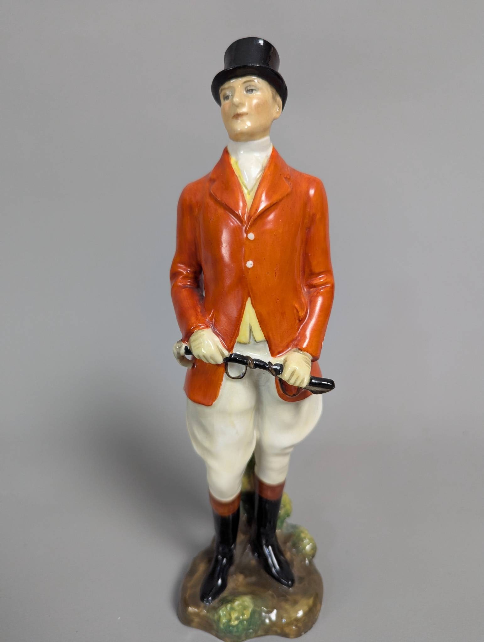 Royal Doulton The Huntsman Early Edition Figurine: Royal Doulton figurine titled The Huntsman, Early Edition, 9 high. Crafted from fine porcelain, the piece features a huntsman in traditional attire with vivid detailing. Markings and stamps on the bas