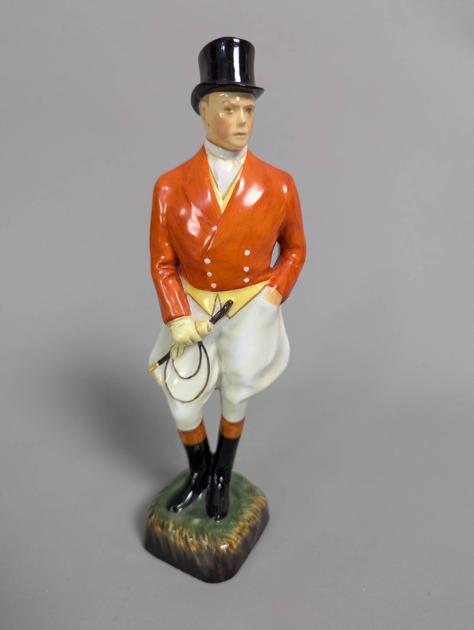 Royal Doulton HN1217 Figure of a Man in Red Hunting Attire: Royal Doulton porcelain figure HN1217 portraying a man in red hunting attire. The figure features fine hand-painted details, including his red hunting coat, white breeches, black boots, and top hat. H