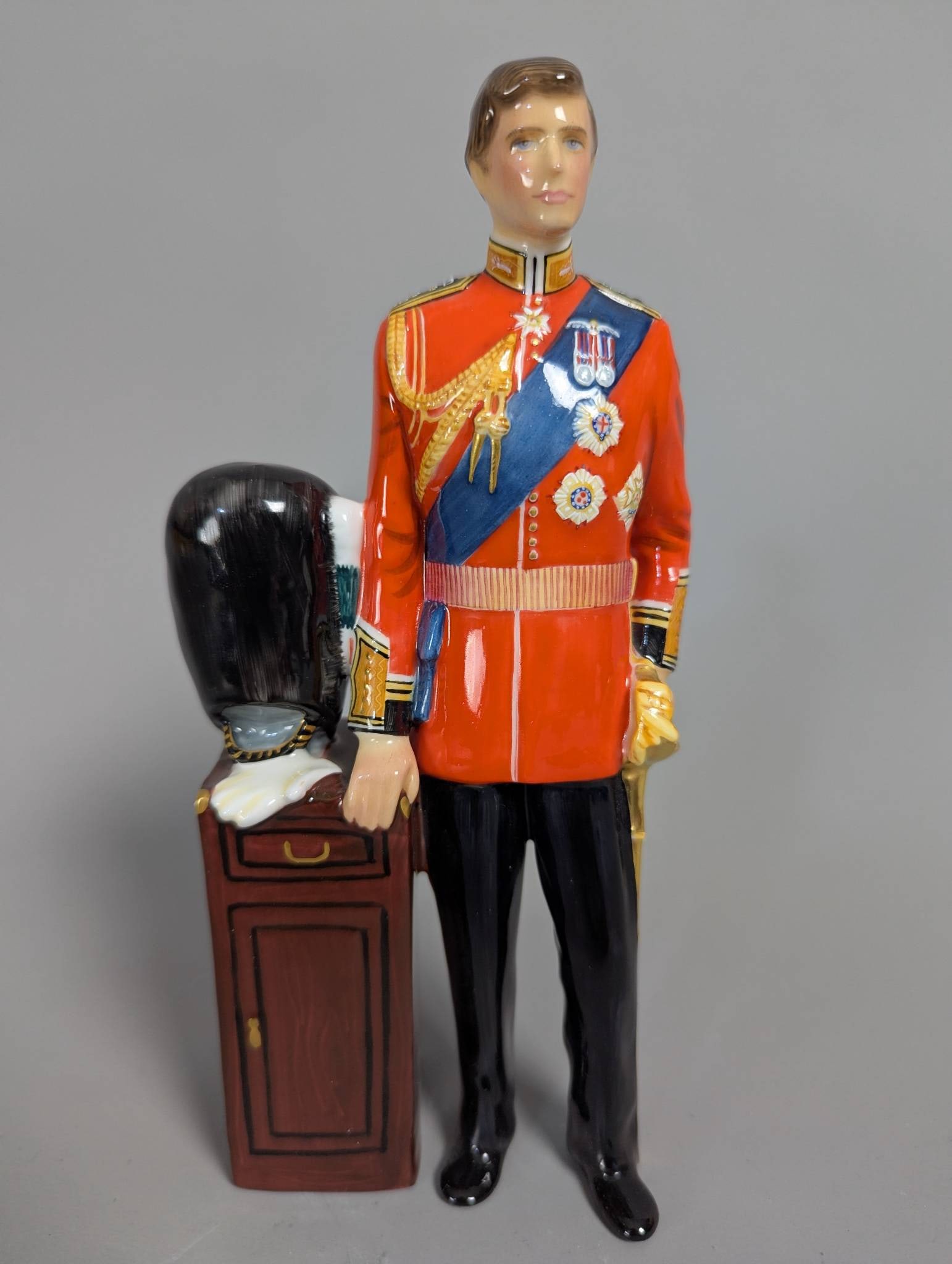 Royal Doulton Hn 2884 HRH The Prince of Wales Figurine w/ Stand: Royal Doulton Hn 2884 porcelain figurine depicting HRH The Prince of Wales. The highly detailed piece portrays the Prince in a red military uniform adorned with royal insignia and medallions, standing