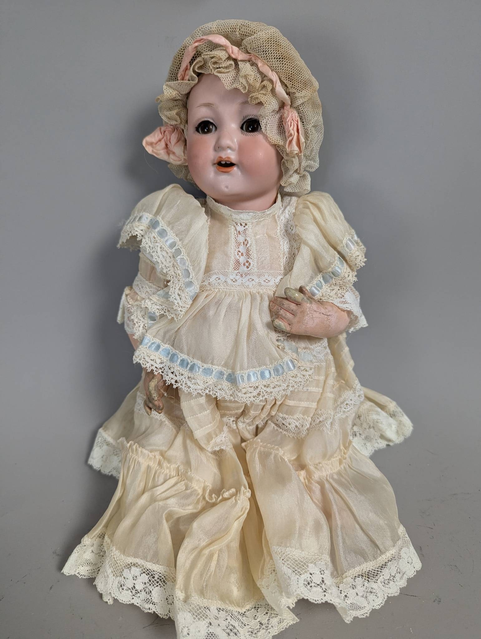 Bisque Doll by Otto Gans with Period Dress: This bisque doll, marked by Otto Gans, measures 14 high. It features detailed facial modeling and a layered period dress of lace and fabric. The doll exhibits signs of wear, with its clothing displayi