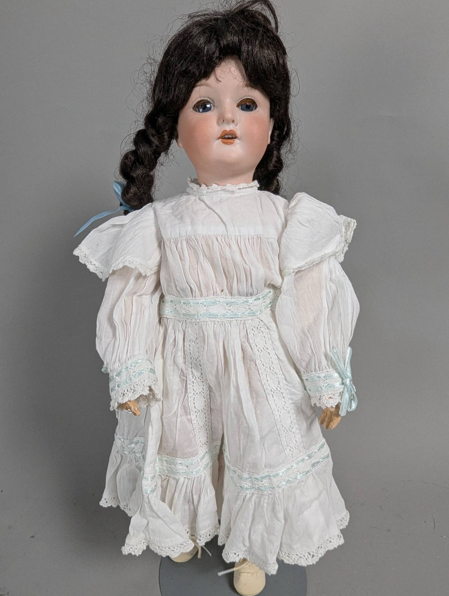 Bisque Head Doll Marked C M Bergmann with Composition Body: Bisque head doll marked C M Bergmann, featuring a composition body and articulated limbs. The head includes detailed hand-painted features, blue sleeping eyes, and an open mouth. The wig features styl