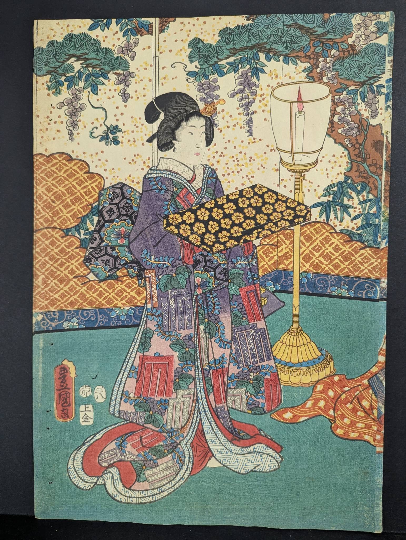 Japanese Woodblock Print Depicting Woman in Traditional Attire: An original 19th-century Japanese woodblock print attributed to Toyokuni III, depicting a woman in intricately patterned traditional attire holding a floral tray. The background features a detailed la