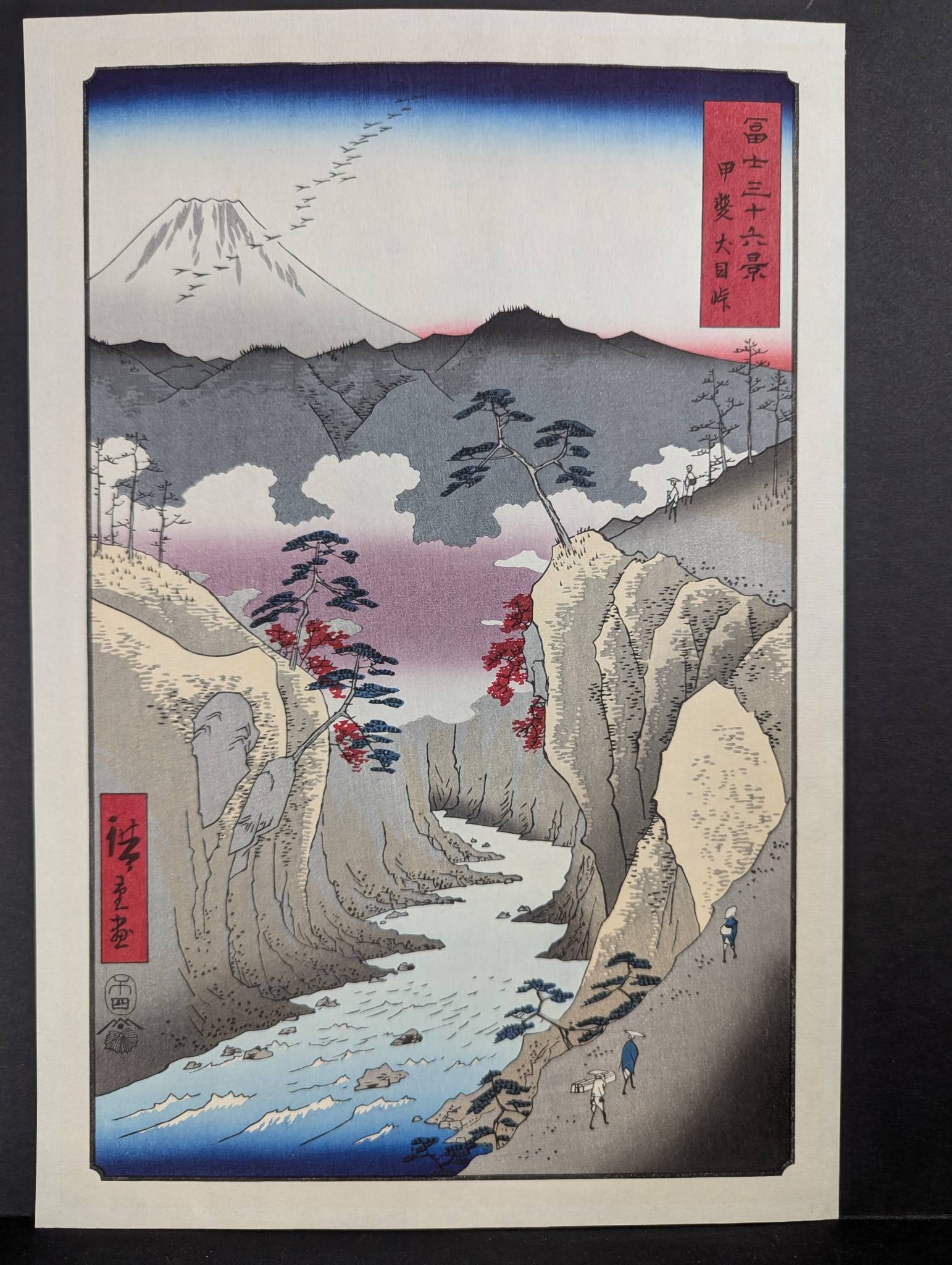 Japanese Woodblock Print Reproduction by Ando Hiroshige from 36 Views of Mt Fuji: A reproduction Japanese woodblock print by Ando Hiroshige from the renowned series 36 Views of Mt Fuji. This piece captures a scenic view featuring Mount Fuji with a flowing river, rugged cliffs, and