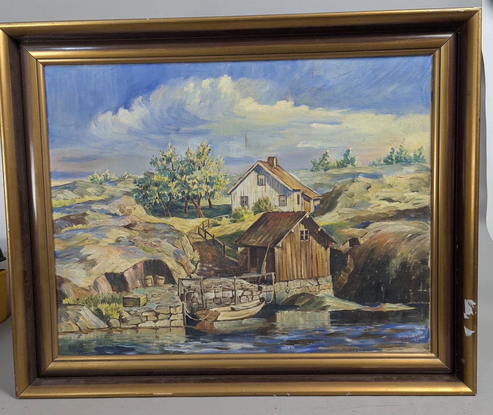 1941 Landscape Painting Signed B Sodal Depicting a Rustic Scene: A 1941 painting signed by artist B Sodal, featuring a rustic landscape with a house, trees, and waterfront structures. The artwork is executed on canvas and exhibits detailed brushwork, suggesting an