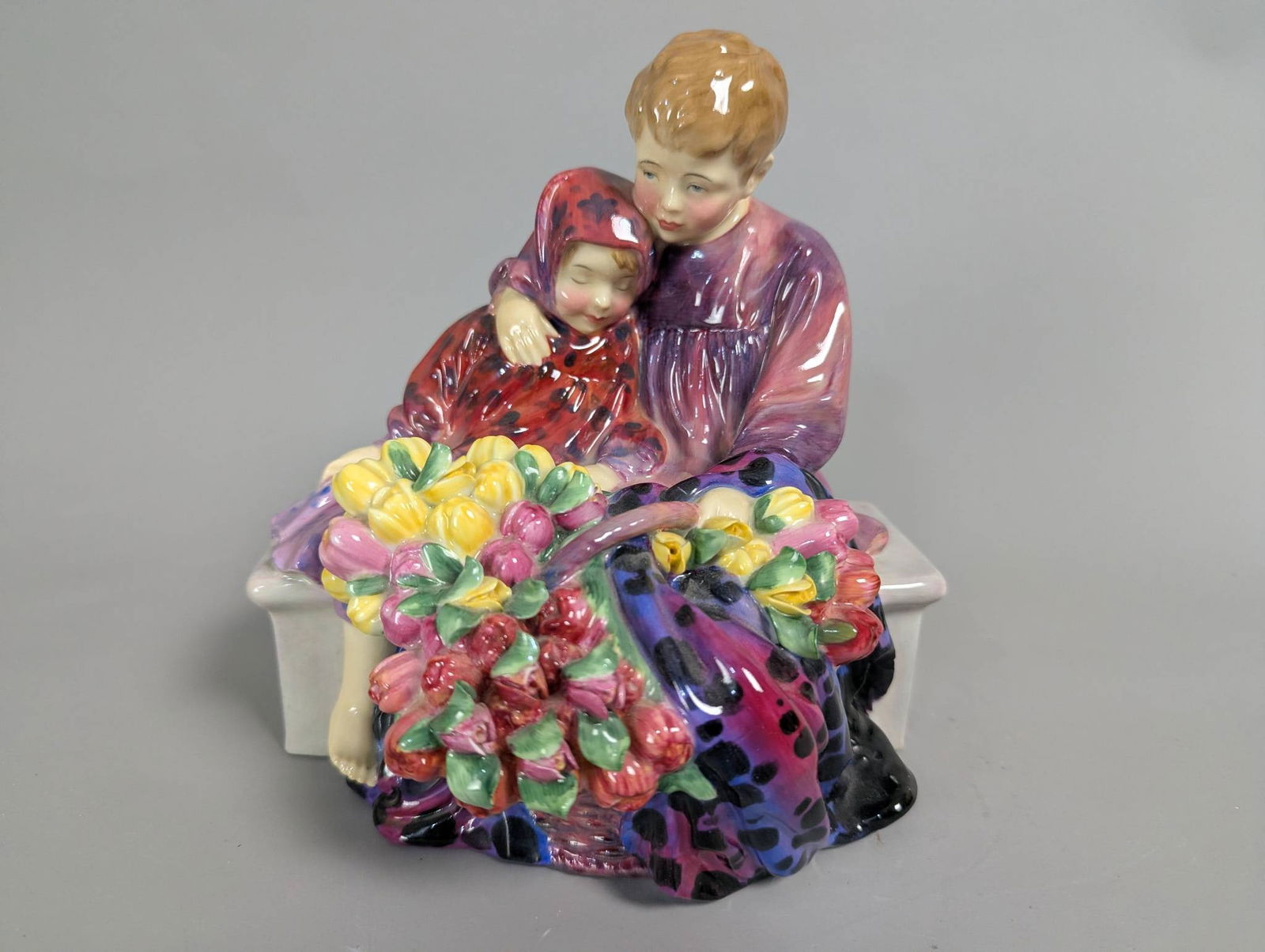 Royal Doulton HN 1342 The Flower Sellers Children Porcelain Figurine: Royal Doulton porcelain figurine, titled The Flower Sellers Children, model HN 1342. Depicts two children seated on a bench with vibrant floral details. Measures 8 inches high, 8 inches wide, and 6 in