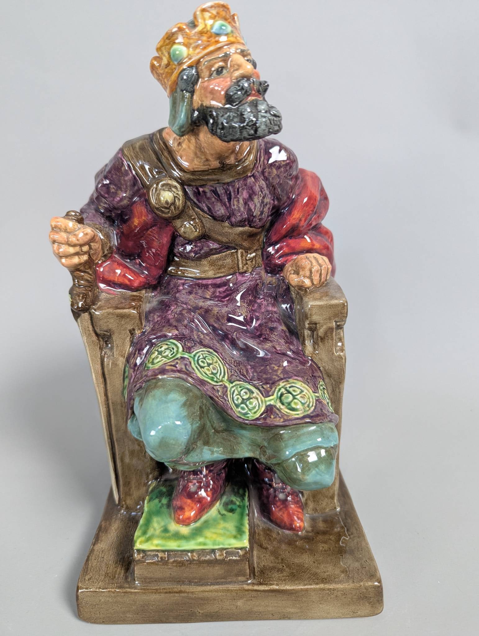Royal Doulton HN 2134 The Old King Porcelain Figurine: Royal Doulton porcelain figurine titled The Old King with the HN number 2134. The piece measures 11 inches high by 6 inches wide by 6 inches deep. It portrays a regal figure seated on a throne, adorne