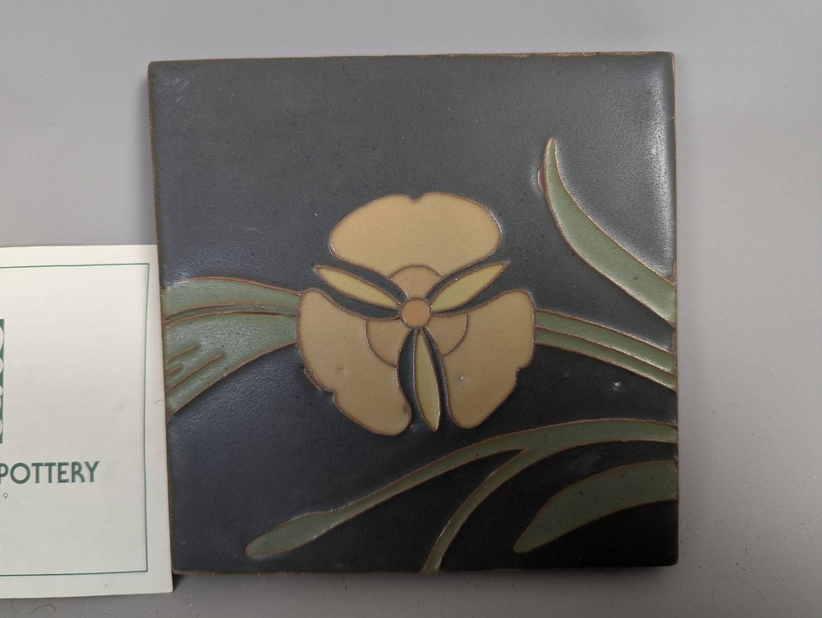 Van Briggle Art Pottery Tile with Iris Motif in Matte Green and Yellow Glaze: Van Briggle art pottery tile featuring an iris motif, executed in a matte green and yellow glaze. Crafted in the Arts and Crafts or Art Nouveau style, this tile is a fine example of the handcrafted tr