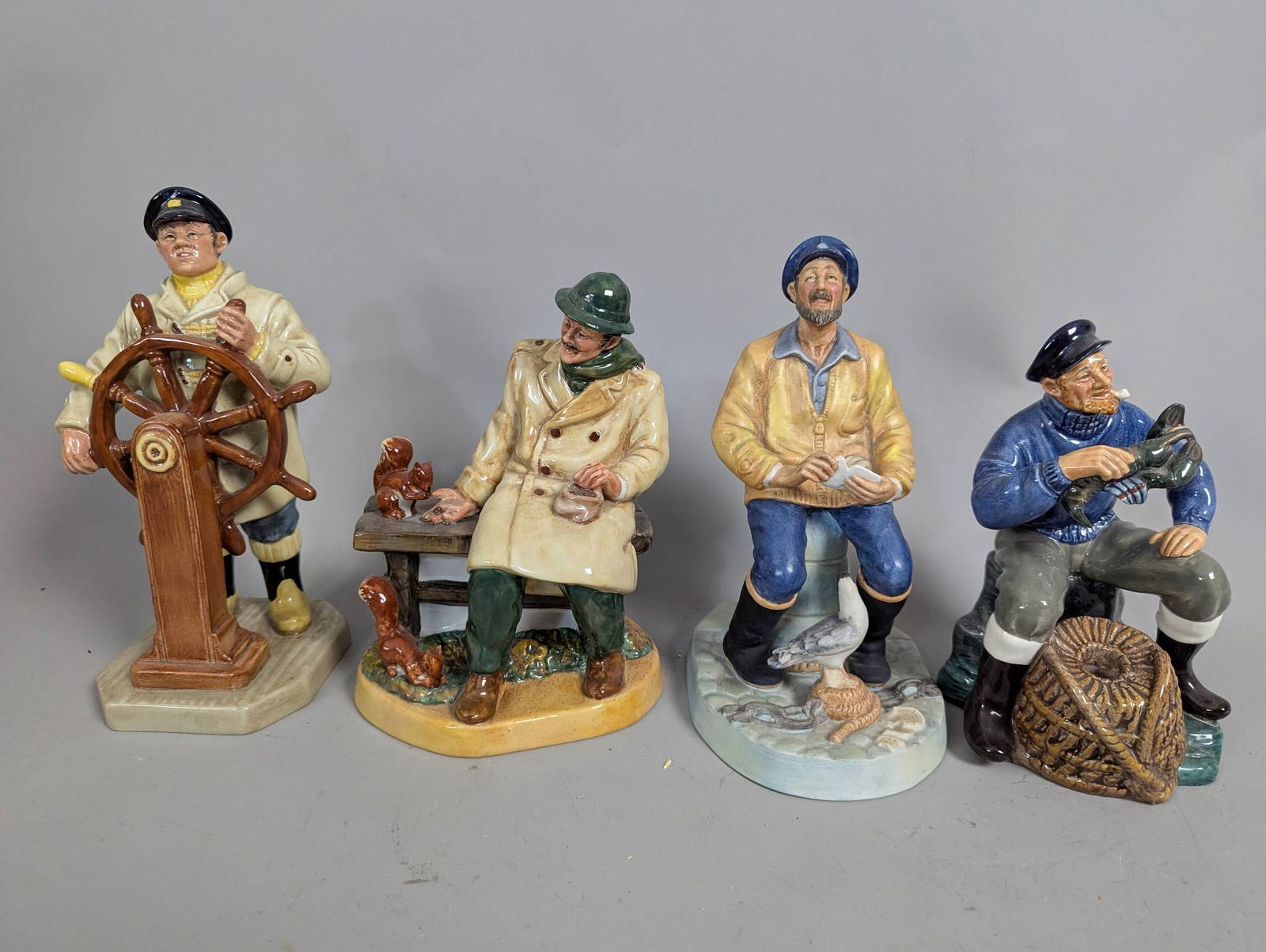 Royal Doulton Figurines Including The Helmsman Lunchtime The Seafarer and The Lobster Man: Four Royal Doulton figurines depicting maritime and nautical-themed characters. The figurines include "The Helmsman" (HN 2499), "Lunchtime" (HN 2485), "The Seafarer" (HN 2455), and "The Lobster Man" (