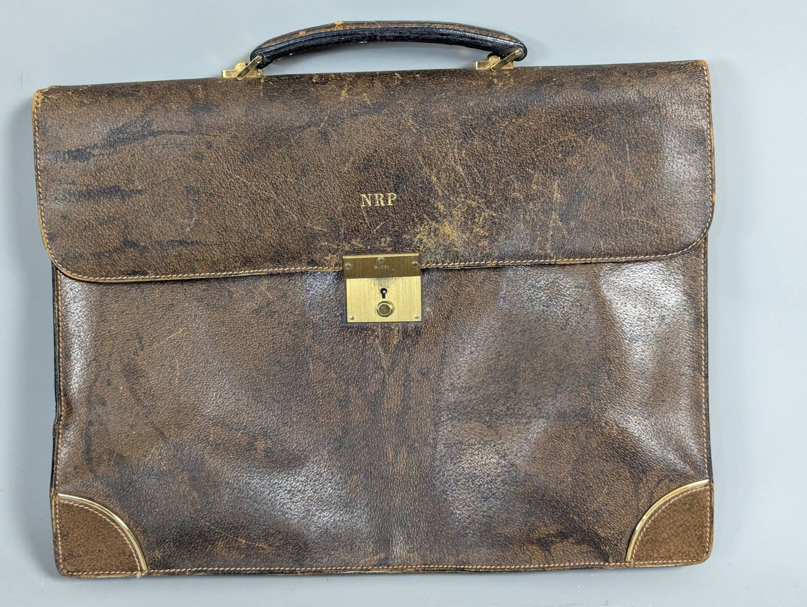 Gucci Brown Leather Briefcase with Gold Tone Hardware: Gucci brown leather briefcase featuring gold tone hardware and a secure lock mechanism embossed with the Gucci logo. Compact with organized internal sections, measuring approximately 16 inches high, 1