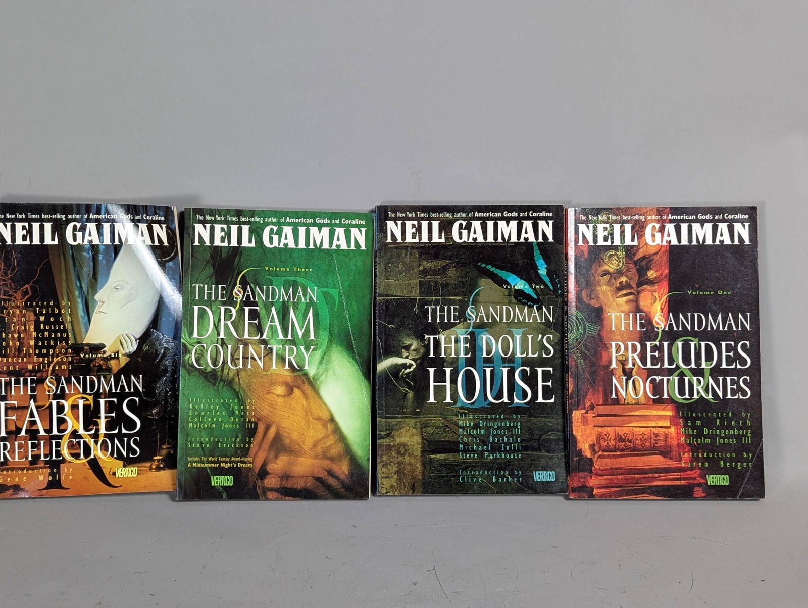 Four The Sandman Graphic Novels by Neil Gaiman: Four volumes from The Sandman series by Neil Gaiman. Includes Preludes and Nocturnes, The Doll's House, Dream Country, and Fables and Reflections. The books are visually illustrated by various artists