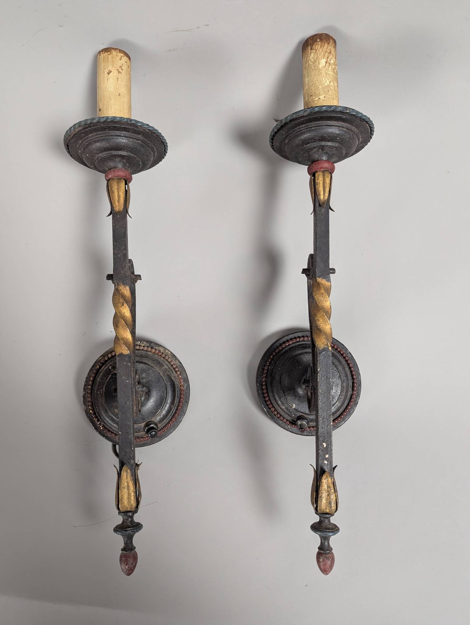Wrought Iron Wall Sconces with Gilt Accents in Gothic Revival Style: Wrought iron wall sconces with gilt accents, likely in a Gothic Revival, Medieval, or Tudor style. Each fixture measures 19 high x 5 wide x 5 deep, showcasing a twisted iron stem with gold-plated acce