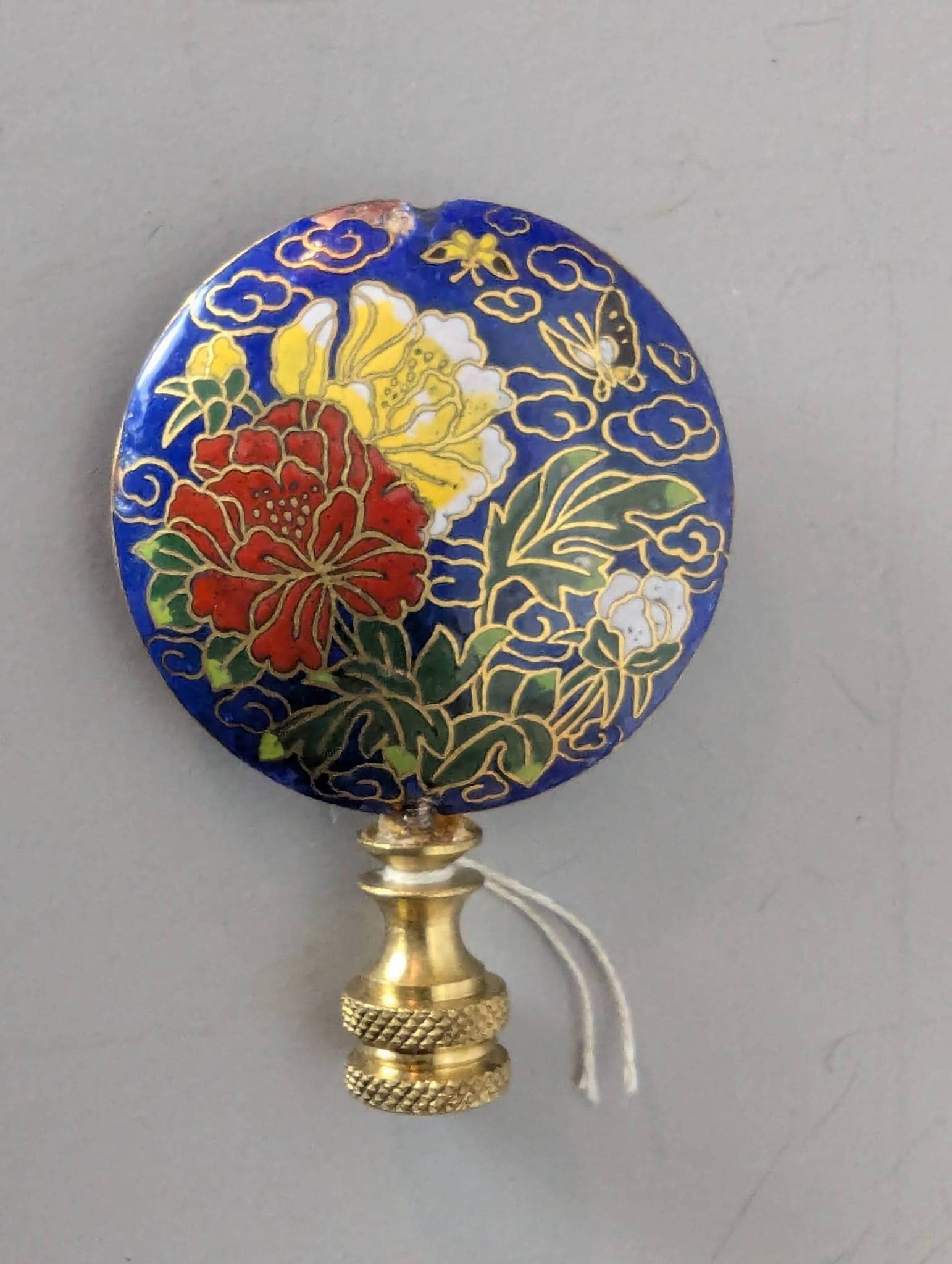 Chinese Cloisonne Floral Lamp Finial with Brass Base: Chinese cloisonne floral lamp finial featuring a vibrant enamel design of flowers and a butterfly against a blue background. The piece incorporates a brass base with detailed texturing for secure