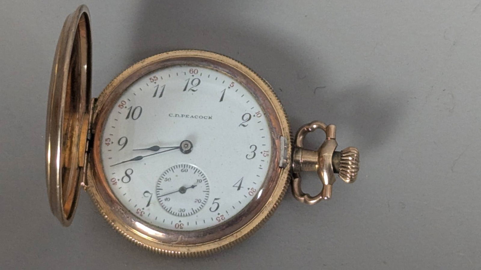 Gold Filled Pocket Watch by Elgin for C D Peacock: Gold-filled pocket watch manufactured by Elgin, marked C D Peacock on the white enamel dial. The watch features Arabic numerals, a small seconds subdial, and black hands. The movement is marked Elgin
