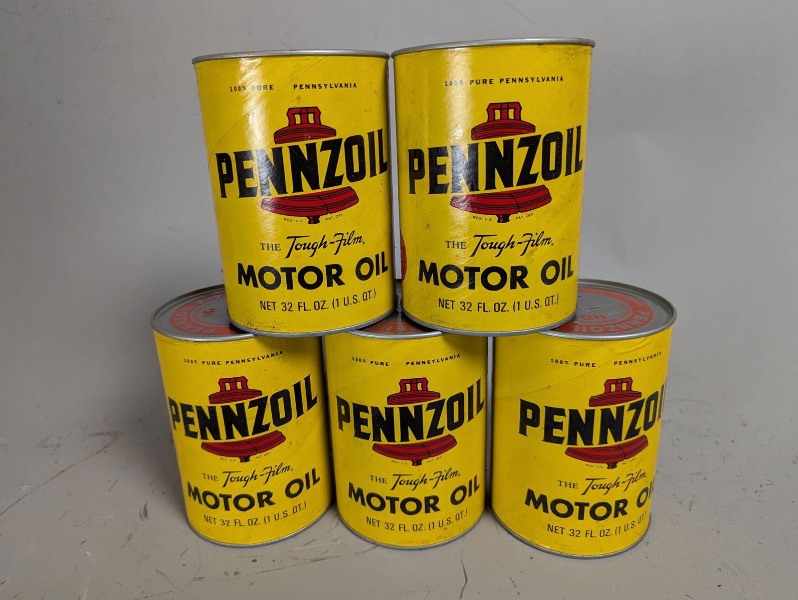 Vintage Pennzoil 1 Quart Motor Oil Cans with Liberty Bell Logo: Five vintage Pennzoil 1 quart motor oil cans featuring the Liberty Bell logo and The Tough-Film slogan. These cans, measuring 5 1/2 inches high with a 4-inch diameter, are collectible items from the m
