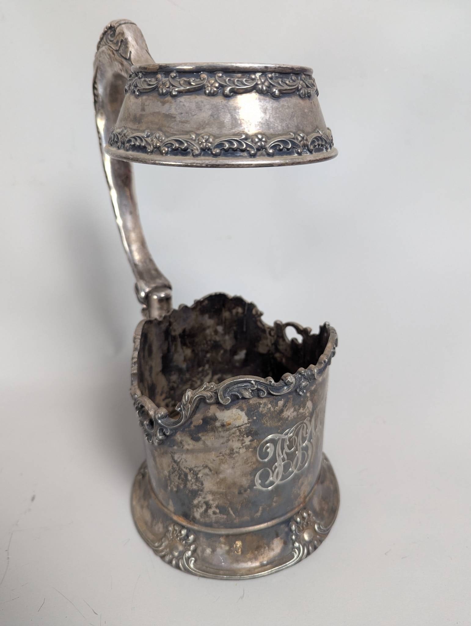 Silver-Plated Beer Stein Holder With Ornate Handle and Monogram: **Important** Please read below description on how to avoid high shipping costs. Silver-plated beer stein holder measuring 11 inches high, 7 inches wide, and 6 inches deep. Features an ornate hinged
