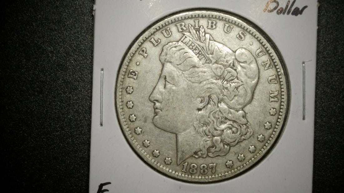 1887-O Morgan Silver Dollar Fine by George T. Morgan - Collectible US Coin: **Important** Please read below description on how to avoid high shipping costs. This 1887-O Morgan Silver Dollar, graded Fine, showcases the rich history and craftsmanship of U.S. coinage. The coin,