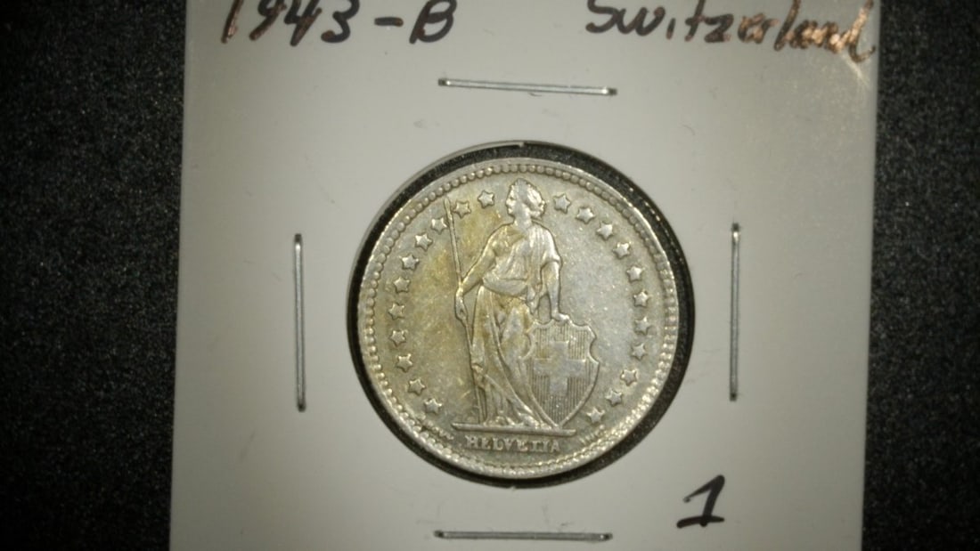 1943-B Switzerland 1 Franc Coin Graded Very Fine by Swissmint, Helvetia Design: **Important** Please read below description on how to avoid high shipping costs. This is a 1943-B 1 Franc coin from Switzerland, graded as Very Fine. The obverse features the iconic standing figure of
