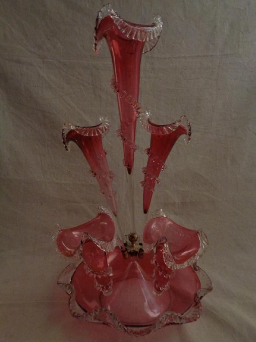 Antique Victorian Cranberry Art Glass Epergne: Hand blown cranberry glass with crimped clear glass edges and crimped clear center twists. Includes base and five arm. (1) Base with small flea bite chip to clear edge. (2) Center arm (screw in) with 