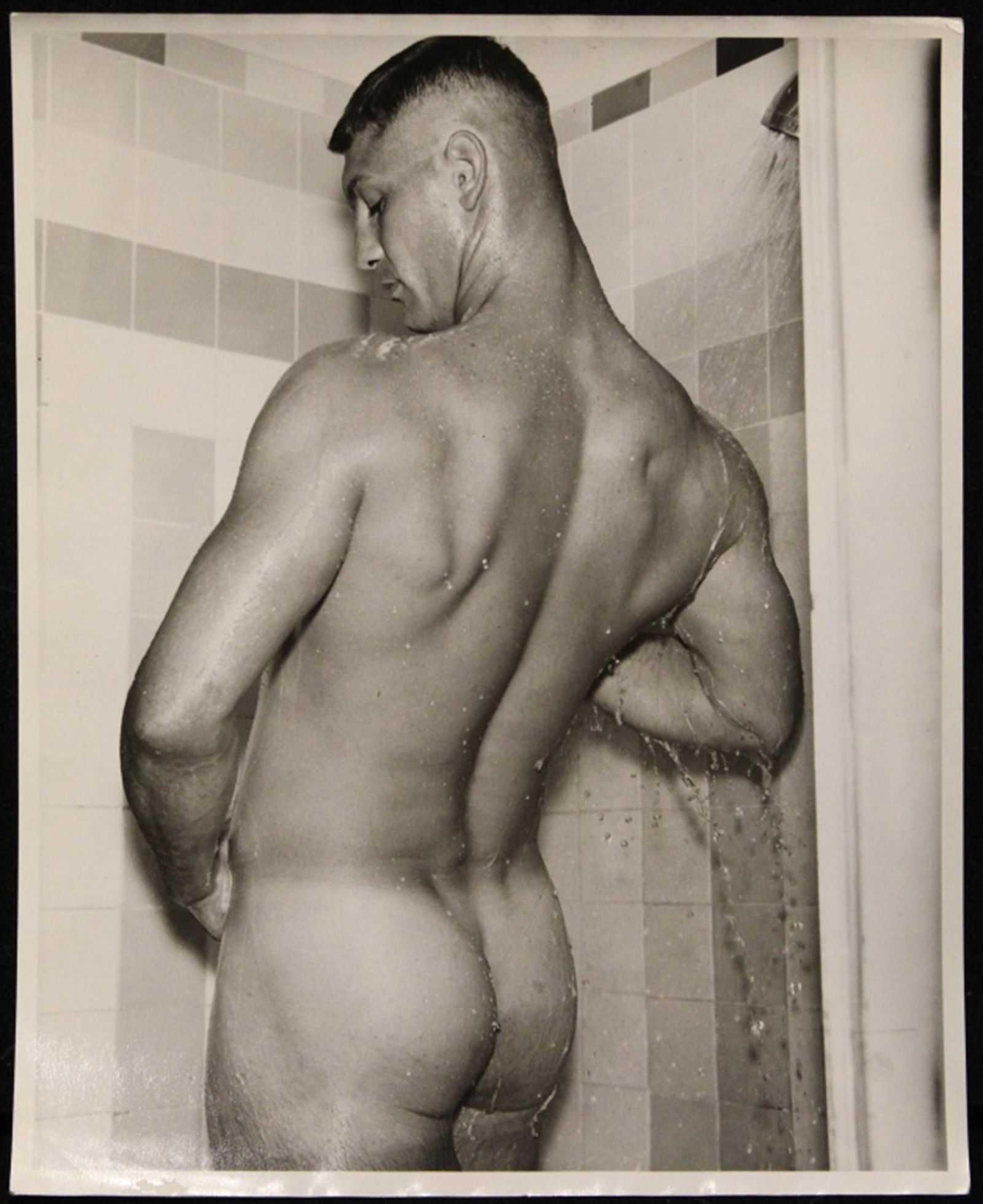 Vintage Bob Mizer AMG Male Nude Photograph: Male nude model with crew cut posed in shower. " UR5-BP" in pencil to reverse. Sharp image with good tones in excellent condition (minor border and edge age wear). 8" x 10" unframed.