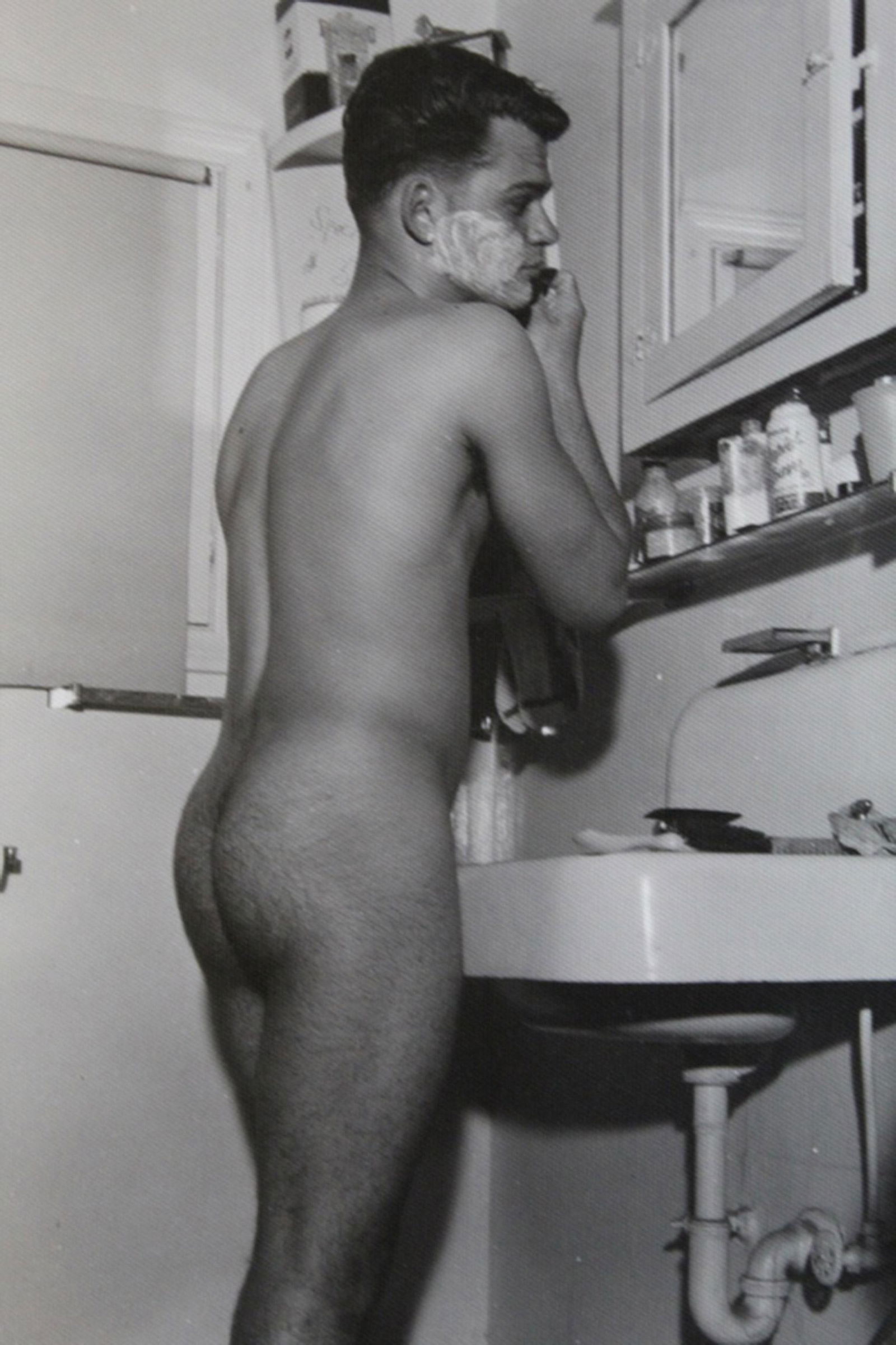 Vintage Bob Mizer AMG Male Nude Photograph: Image of a man shaving at bathroom sink. Pencil numbered XI15-J and 35 to reverse. Printed on double weight textured satin paper. Excellent sharp clear image, 1950's. 5" x 4".