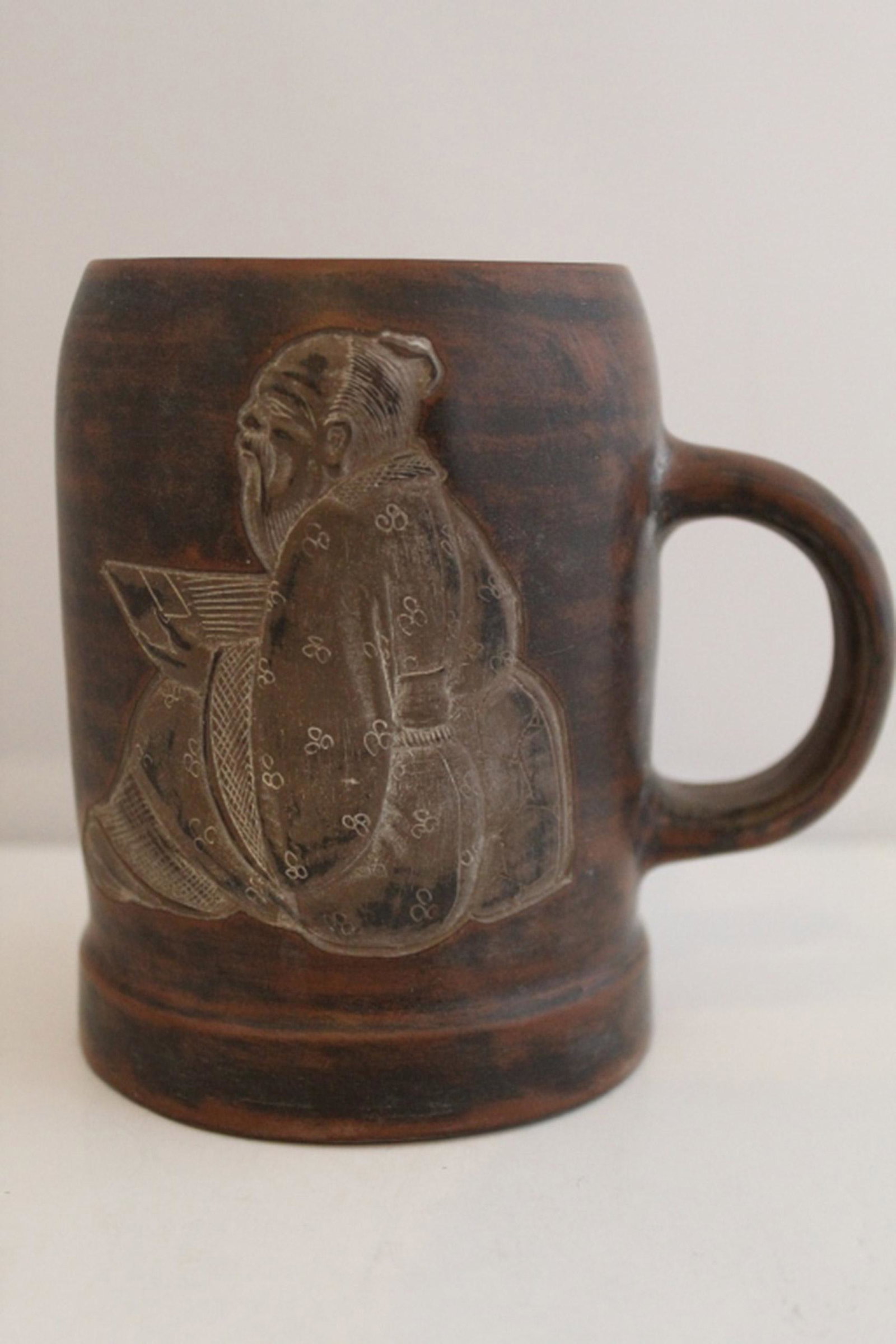Vintage Chinese Yixing Clay Tea Mug: Hand formed red clay with black burnished finish. Sunk relief carved scholar figure to one side; carved Chinese character writing to the other. Etched mark to base. 4.5" H