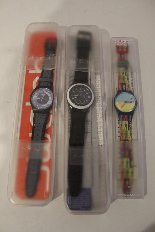 Three Vintage Swatch Watches: (1) The Originals GS105 Lucky Shadow watch with case and pamphlets. (2) Swatch Irony YPB401 Lounge watch with case and pamphlets. (3) Electric Hours SUJB702 Date Day Dial in blue with case. All excell