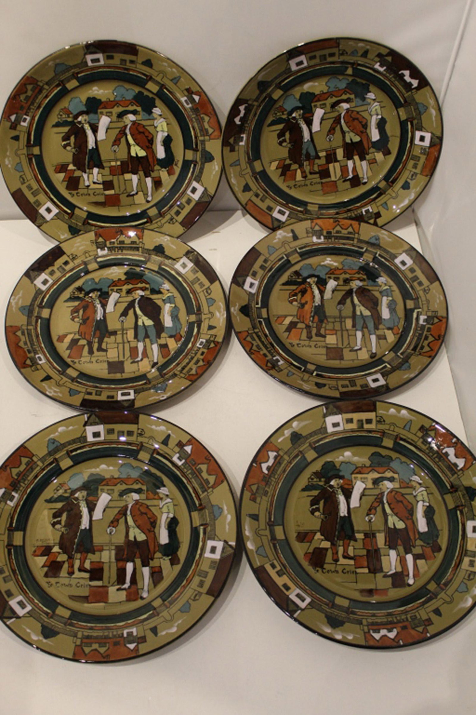 1908 Buffalo Pottery Deldale Ware Plates: Set of 6 "Ye Town Crier" plates. Hand painted street scene of 18th C. style figures. A. Delaney, L. Wit, L. Streissel, and H. Ford artist signatures to 4 plates. Maker's marks to bottoms. All excellen
