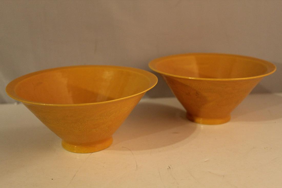 Pair Reproduction Ming Dynasty Porcelain Bowls: Hongzhi style yellow glazed porcelain bowls with incised double dragon designs. Marks to bottoms. Excellent condition. 2.75" H x 6" dia. each.
