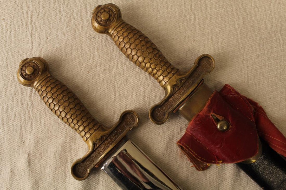 Pair Henderson Ames Odd Fellows Short Swords: Pair Henderson Ames late 19th Century Odd Fellows ceremonial short swords with bronze grips and original scabbards; red belt included in lot. Wear to grips; wear and areas of rust on blades; some wear