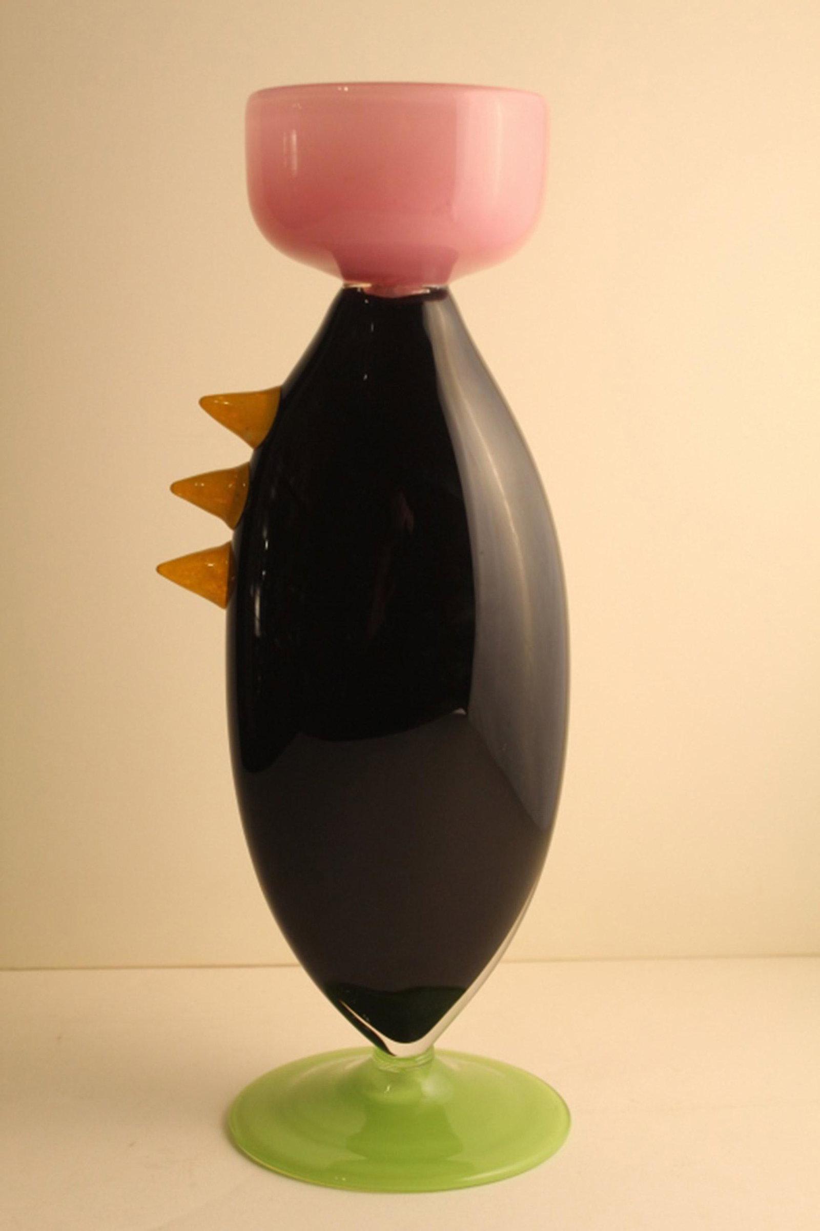 Memphis Style Studio Art Glass Vase: Hand blown vase in pink, black, green, and yellow cased glass. No apparent signature. Tiny flake chip to underside of base. 14.5" H.