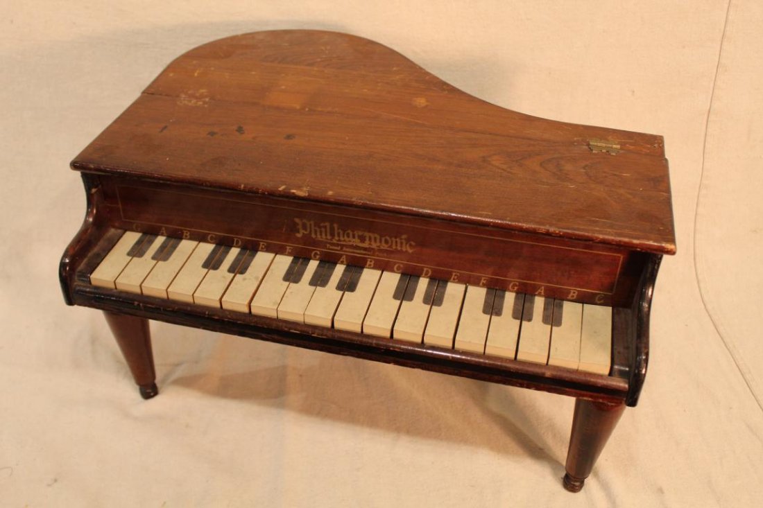 Vintage Philharmonic Toy Baby Grand Piano: "Philharmonic Tuned International Pitch". Mahogany and pine case with 18 painted keys and18 musical bars. Three turned wood legs. Original J.C. Penny Co. price tag. Working condition. Original finish 