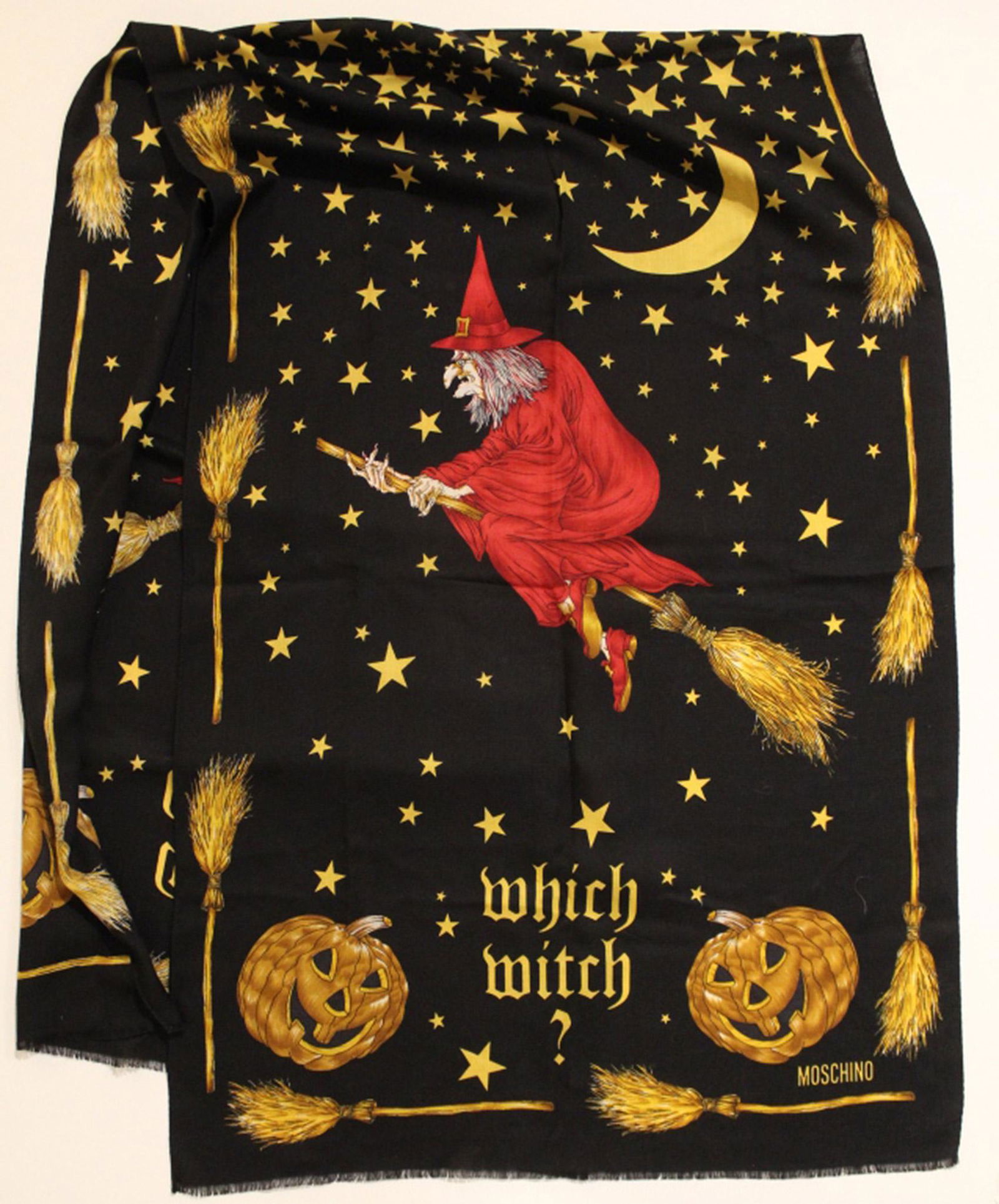 Moschino Wool Scarf: "Which Witch?" wool scarf with double witch on a broomstick design with pumpkins, stars, and cresent moons. Very good condition with no apparent snags, pulls, damage, etc. 25" x 76" approx.