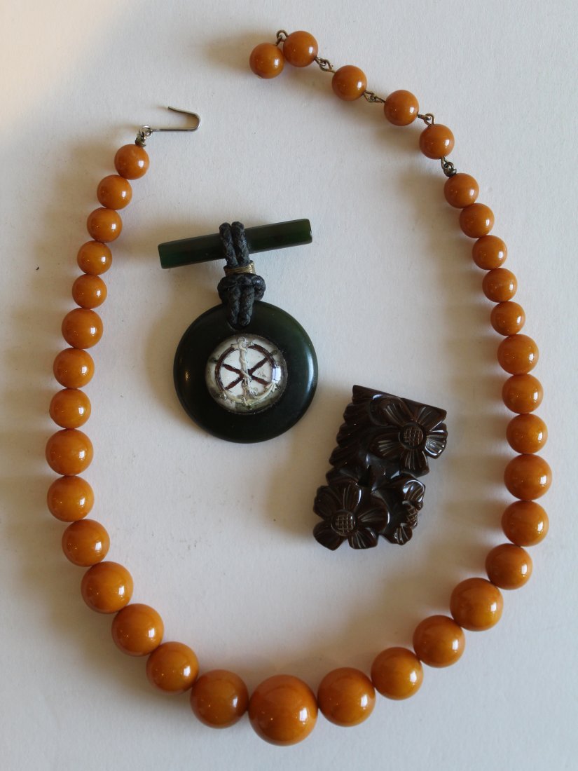 Bakelite Bead Necklace Anchor Pin Scarf Pin: (1) Egg yolk butterscotch bakelite graduated bead necklace with hook clasp. 16.5" L. (2) Green bakelite pin with anchor and ship's wheel medallion under curved glass. 2 1/8" length. 1 1/2" dia. (3) Br