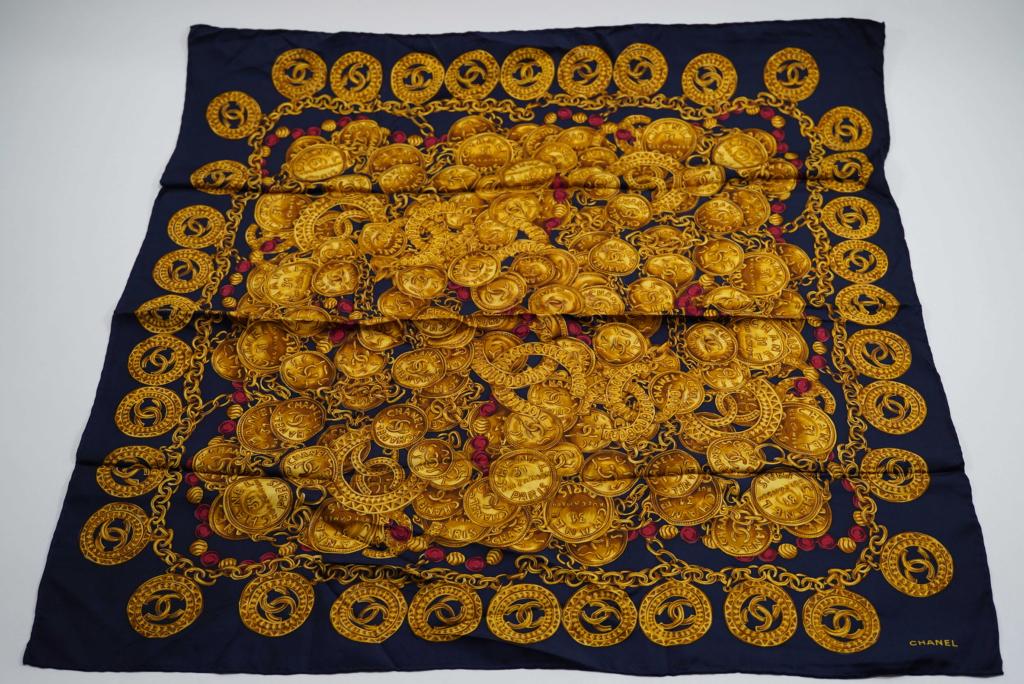 Chanel Silk Scarf: Gold coin and red bead/ gold chain design on a black background. Hand rolled and stitched edges. Original Made in Italy tag. Excellent condition with bright colors. No apparent snags, pulls, damage, e