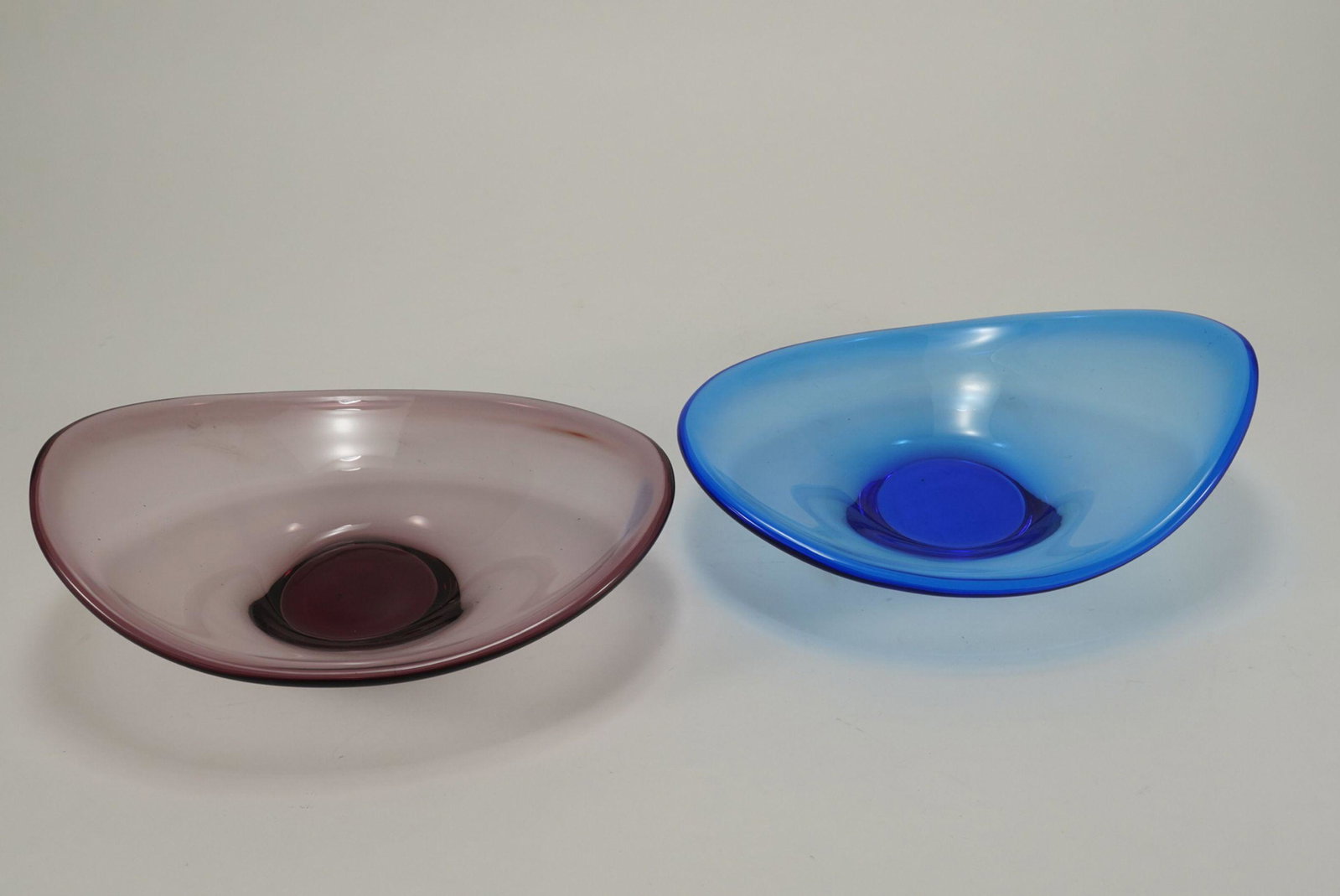 Pair Scandinavian Hand Blown Glass Bowls: Mid century modern style matching shapes bowls in amethyst and blue glass. No apparent signatures or marks. Excellent condition. 3.5" H x 10.25" x 8" each approx.