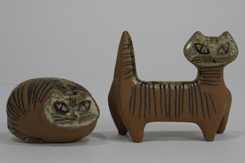 Lisa Larson for Gustavsberg Pottery Cats: (1) Sittng curled cat. Remnant of original label to bottom. Excellent condition. 2" H x 3.75" W x 2.5" D approx. (2) Standing cat. Broken off and reglued tail. 3.75" H x 4.75" W x 1.75" D approx.