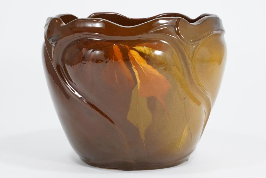 Weller Pottery Louwelsa Jardiniere: Molded Art nouveau pottery jardiniere decorated with burberry leaves on brown / tan glaze. Unmarked. Small glaze chip to left of leaves near lip. Circa late 19th/ early 20th C. 9.75" H x 12" dia.