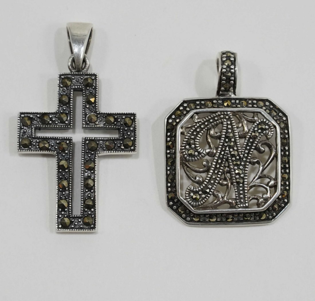 Sterling and Marcasite Pendants: (1) Open work maracasite set pendant with hinged bail. "N" ititial. Marked THAILAND A 925. 7 grams approx. 1 3/8" (including bail) x 1". (2) Crucifix pendant set with maracasite. Stamped 925. 6 grams 