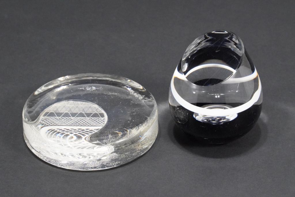 Murano Style Mod Art Glass Paperweights: (1) Hand blown paperweight; air bubble sitting in black with white ring above. 3" H x 2.75" dia. approx. (2) Cast glass paperweight with inset white latticino glass panel. 1" H x 4" dia. Both unsigned