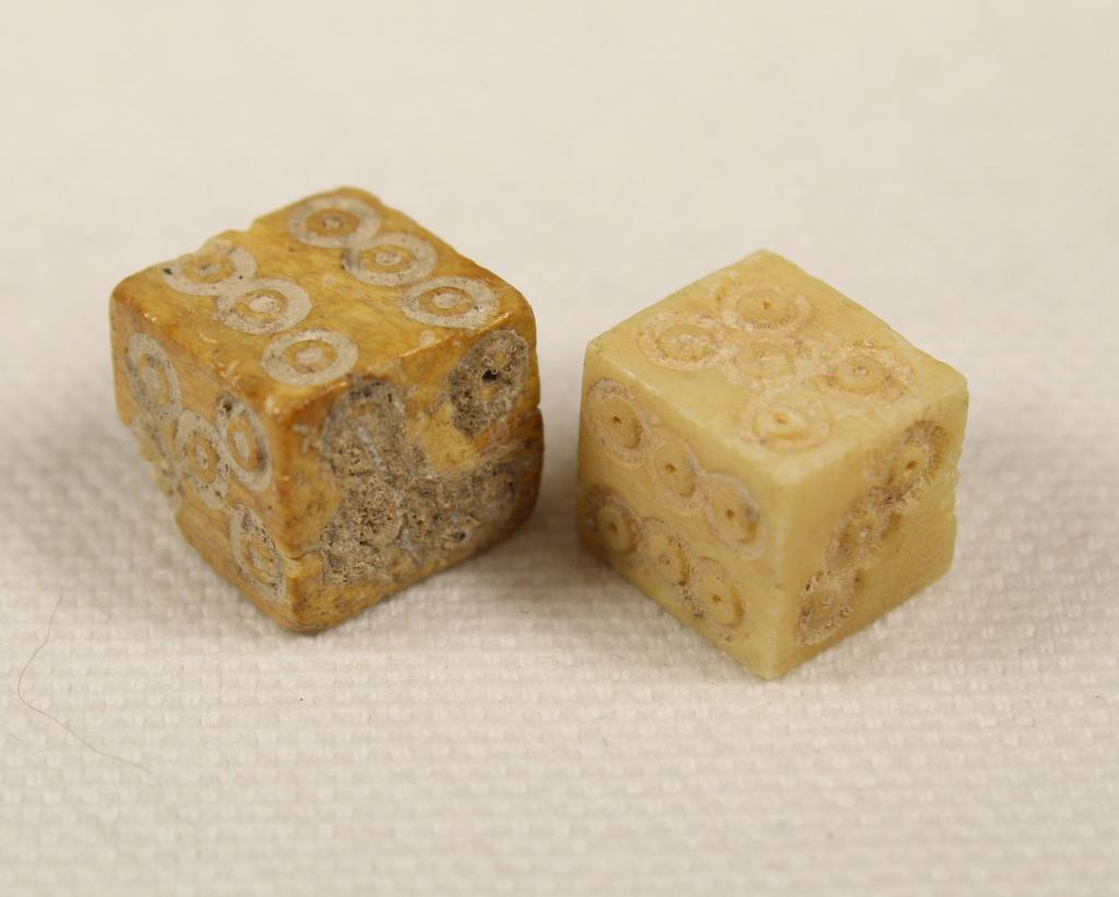 Ancient Roman Bone Gaming Dice: Two carved bone gaming dice, circa 1st to 3rd century AD (one possibly a reproduction). 7/16" x 3/8" x 3/8" and 7/16" x 7/16" x 3/8" (small corner chip) approx.