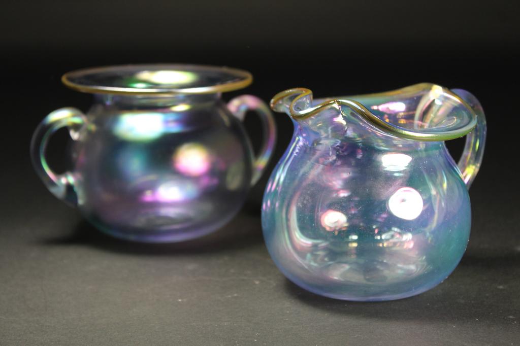 Studio Art Glass Handled Bowl & Small Pitcher: (1) Double handled bowl with satin iridescent surface and gilt lip edge. 3 3/8" x 4" lip dia. (2) Handled pitcher with gloss pale iridescent surface. 3.75" H. Both unsigned; excellent condition.