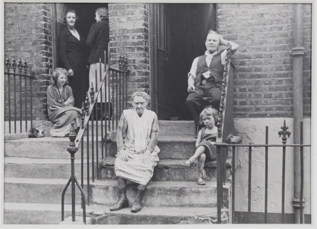 Ellen Auerbach Gelatin Silver Photograph 1935: "London, England", 1935. Image of neighbors on row house stoop. Titled, dated, signed (in pencil and ink) to the reverse along with Auerbach's stamp and other notations. Hinge mounted in presentation