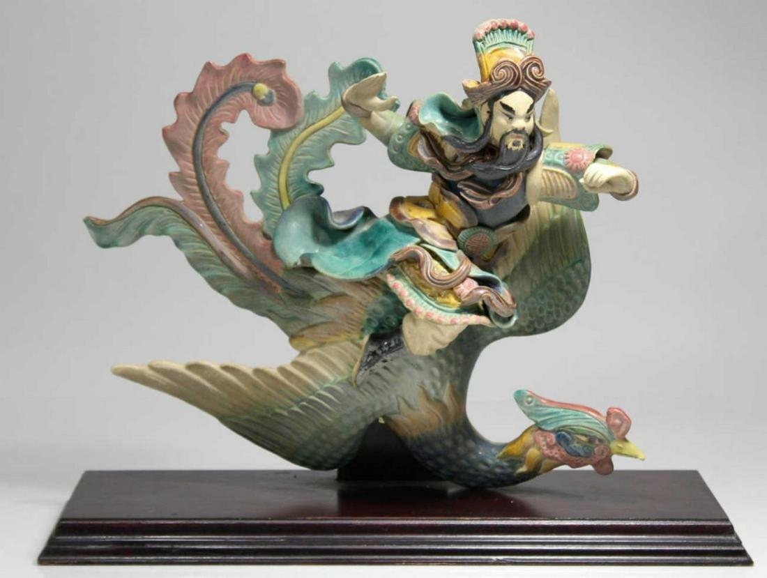 Vintage Chinese Porcelain Roof Tile Warrior: Vintage authentic Chinese roof tile sculpture on wood stand. Tile warrior riding on phoenix bird. Good condition, some wear but no apparent chips, cracks or repairs. On stand measures 11.5" tall, tile
