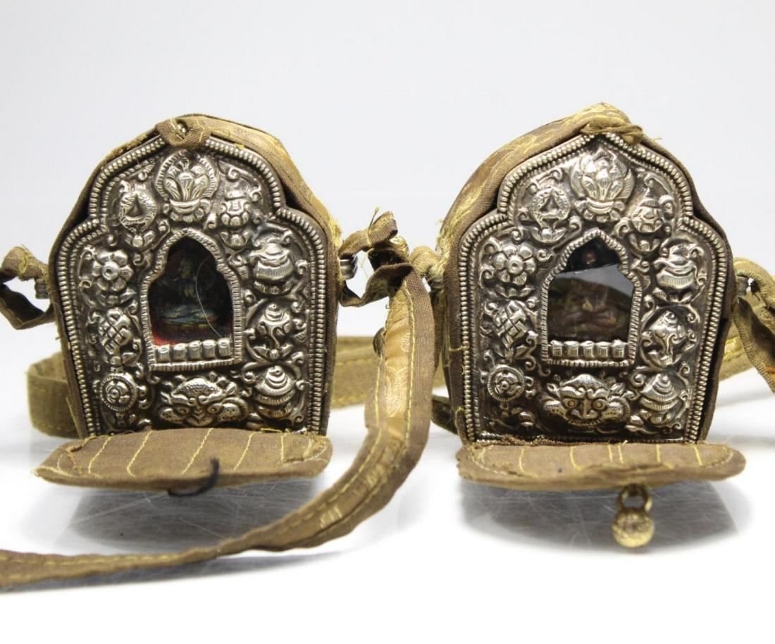 2 Tibetan Traveling Shrines w Silk Cases: 2 Tibetan Traveling Shrines w Silk Cases, the shrines win silver metal repousse and a buddha figure with a glass cover, clasp button missing on one, glass cracked on one, 3" X 3.5"