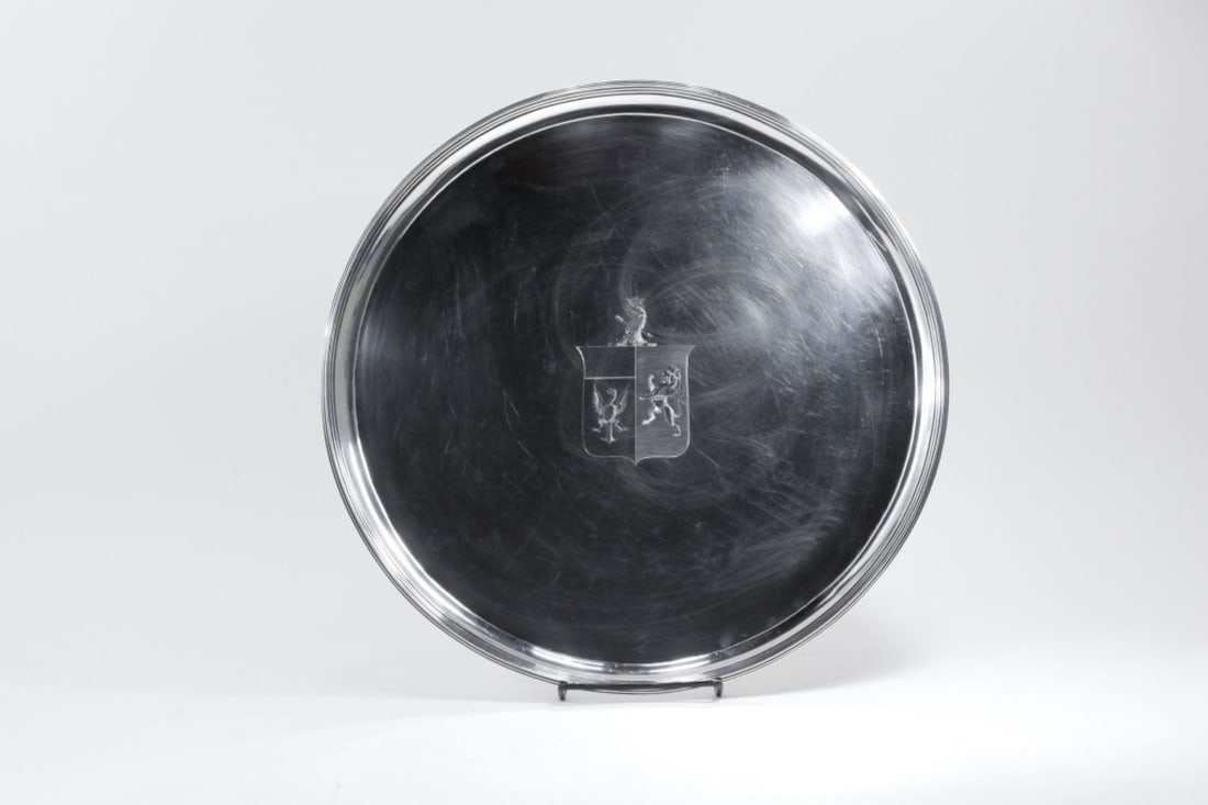 George III Silver Salver John Hutson London 1796: Sterling silver salver tray on four feet. Center engraved with heraldic shield coat of arms top by a crowned dragon with arrow through neck. Maker's mark and London hallmarks with date letter for 1796