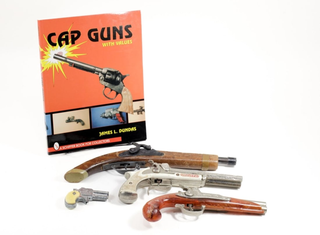 Lot of 4 Vintage Flintlock Cap Guns and Book: (1) Disney Pirates of the Caribbean flintlock pistol, approx 14". (2) Hubley Derringer cap gun, approx 3", (3) Hubley flintlock double barrel cap gun, plastic orange handle with metal barrel, approx.