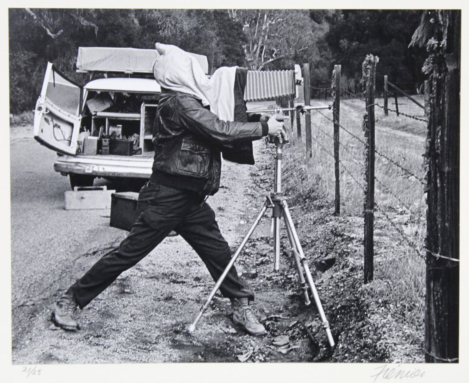 Roger W. Fremier (1939-2011, CA) Self Portrait: Gelatin silver print mounted to mat. Self portrait depecting Fremier posed on roadside hooded with large camera on tripod. Pencil numbered 21/25 and signed to mat below image. Photographer's stamp to 